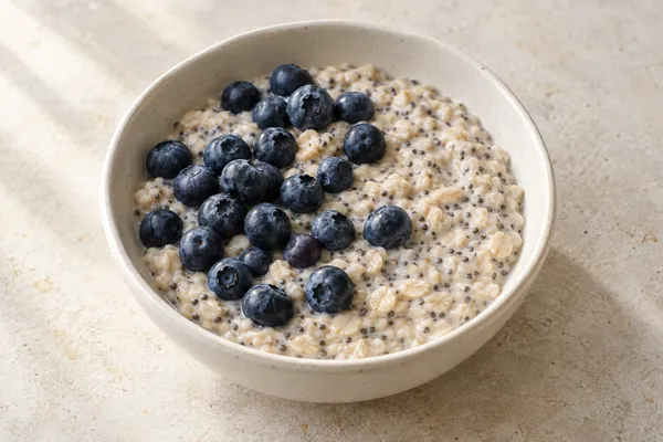 Creamy oats with chia seeds and blueberries in a simple ceramic bowl