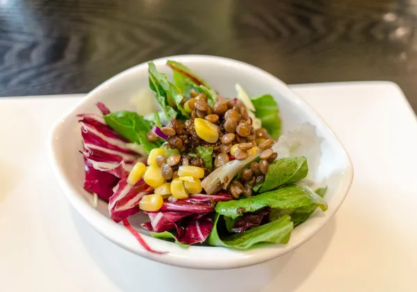 Lentils and sweetcorn served over green and red salad leaves