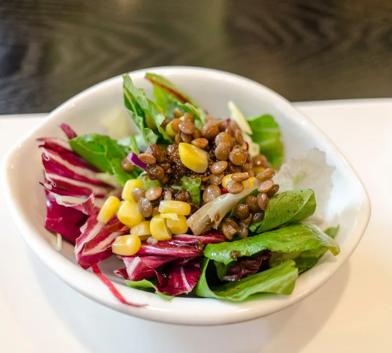 Lentils and sweetcorn served over green and red salad leaves