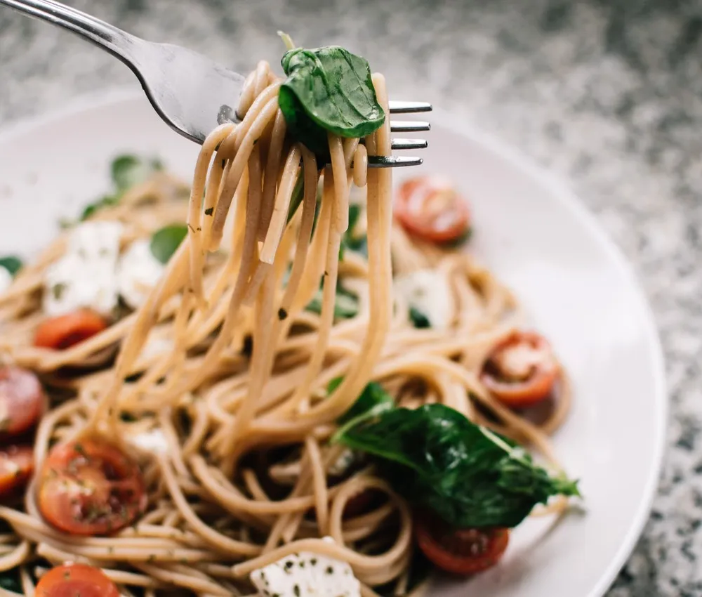 Whole-wheat spaghetti with tomatoes, spinach and crumbled white cheese