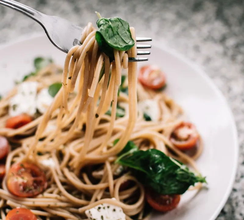 Whole-wheat spaghetti with tomatoes, spinach and crumbled white cheese