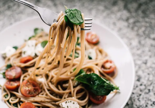 Whole-wheat spaghetti with tomatoes, spinach and crumbled white cheese